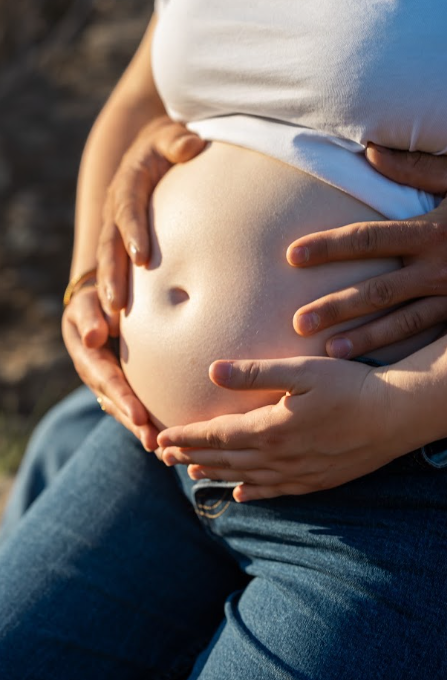 Mains des futurs parents posées sur le ventre rond
