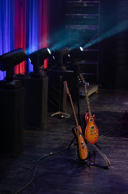 Guitares posées sur leur pied devant les projecteurs