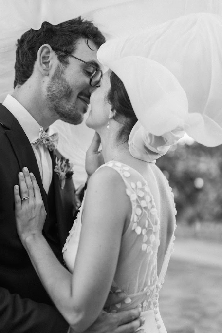 Baiser des mariés en noir et blanc, mariée au chapeau