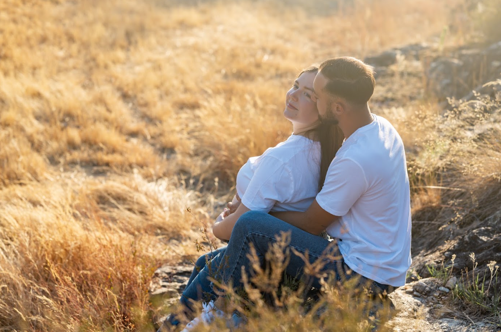 Couple assis dans les herbes au coucher du soleil