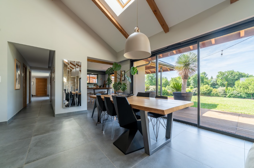 Salle à manger sous charpente ouverte sur le jardin