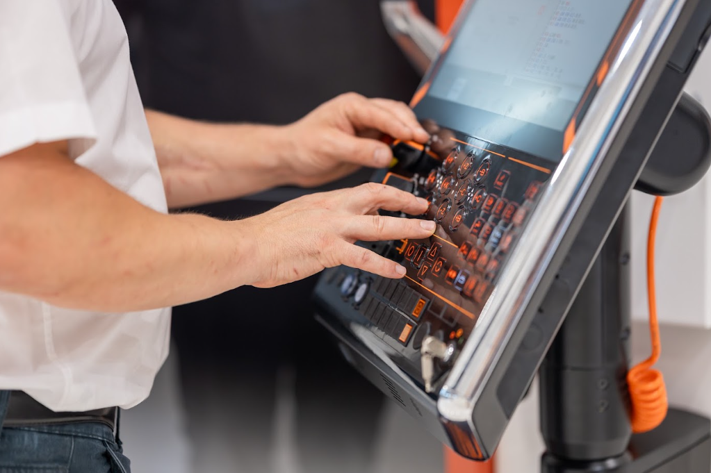 Mains d'un opérateur sur le pupitre de commande d'une machine