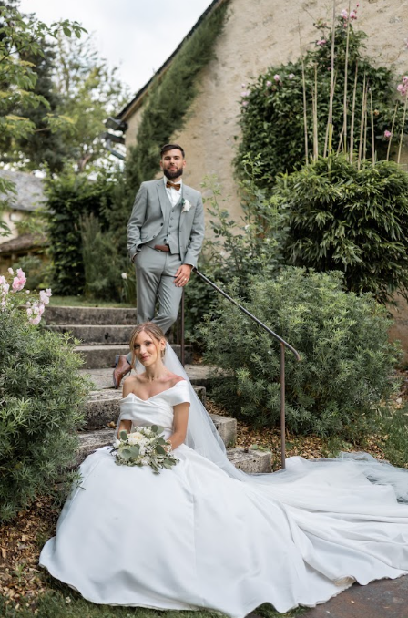 Les mariés posant dans un escalier de pierre entouré de verdure