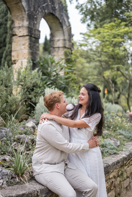 Couple enlacé devant un aqueduc en pierre dans un jardin