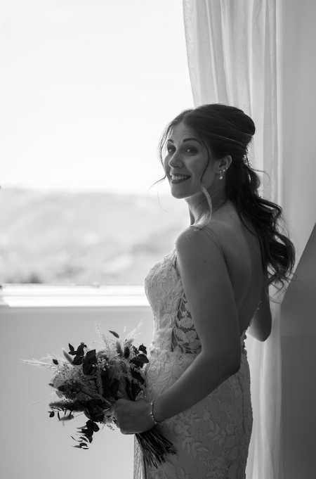 Portrait de la mariée à la fenêtre avec son bouquet, noir et blanc