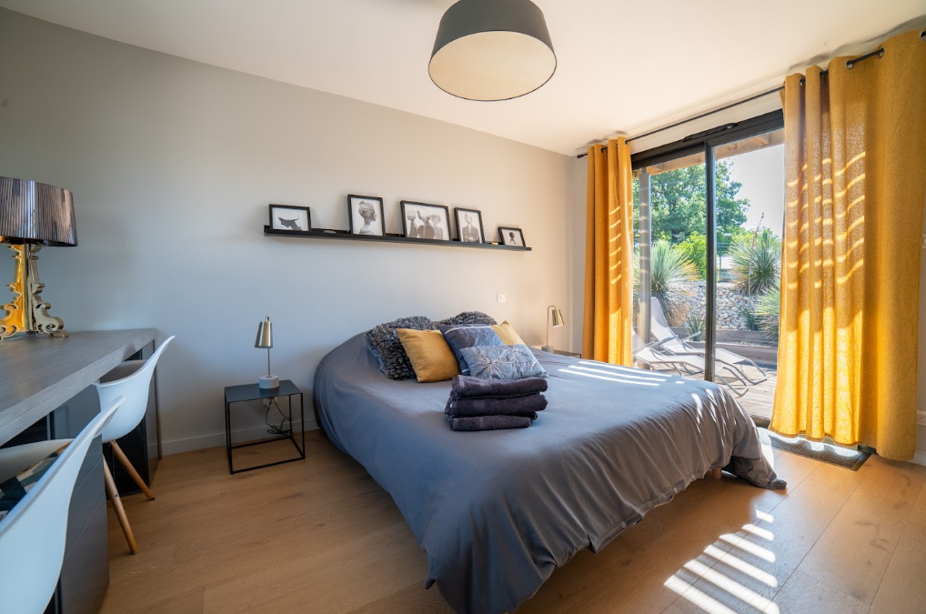Chambre grise ouverte sur la terrasse avec rideaux moutarde